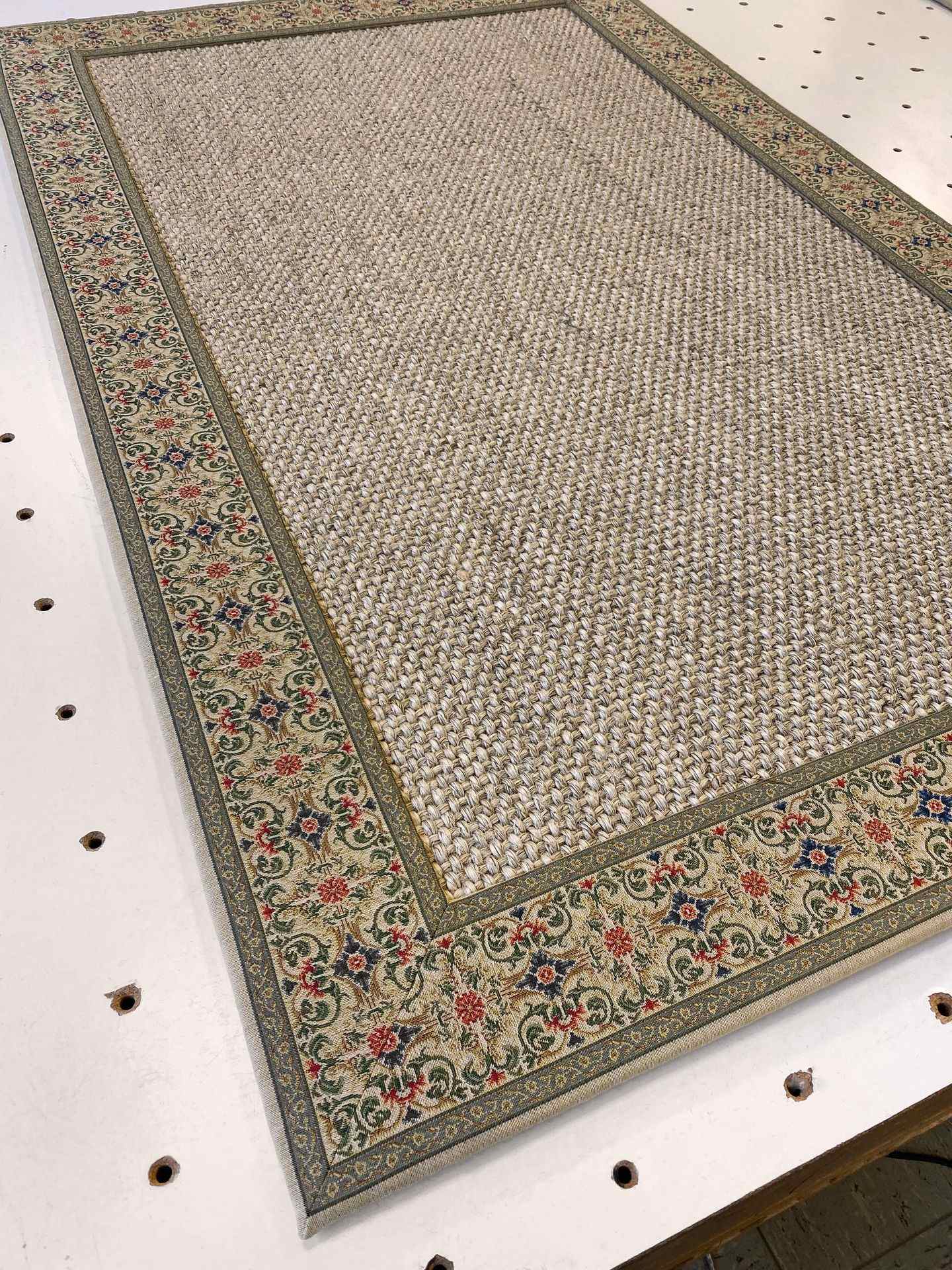 Photo of a sisal rug with an intricately jacquard-woven border in a classic style, backed with hidden stitching.