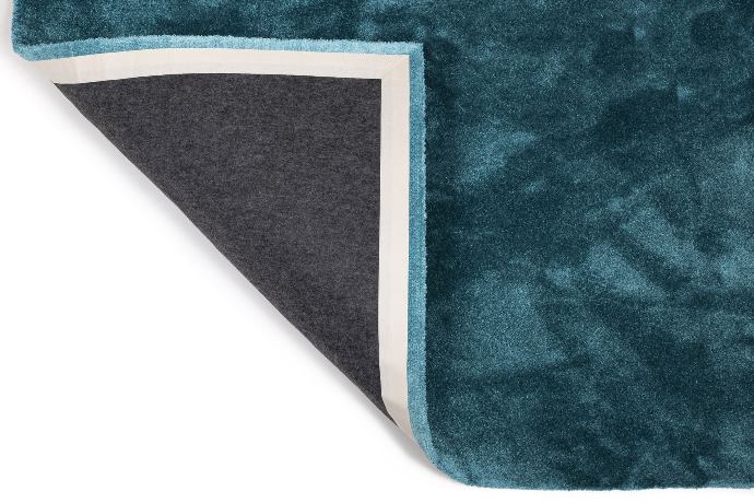 Photo of a turquoise-blue Seestoff rug with a flipped over corner so once can see the felt backing and the edges.