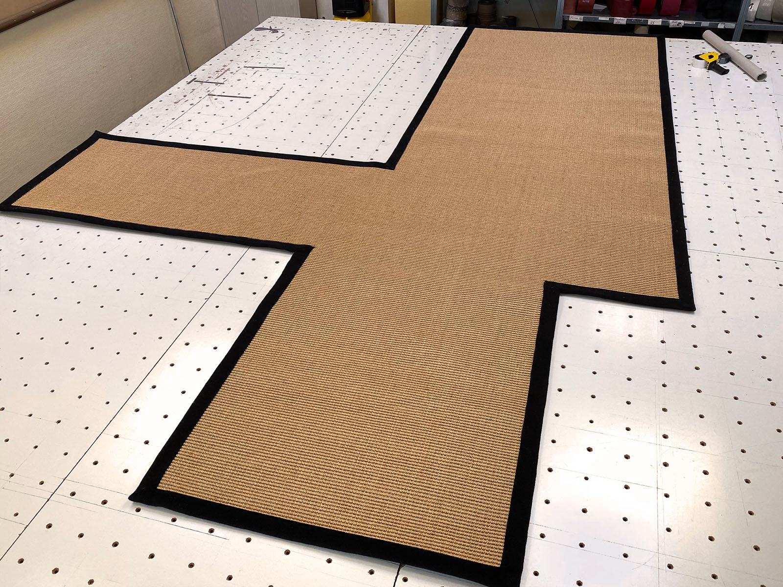 Photo of a sisal rug in production, made from a template, with a black cotton border.