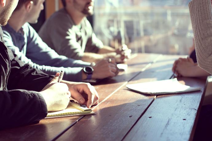 Photo of several people sitting at a table and discussing something.