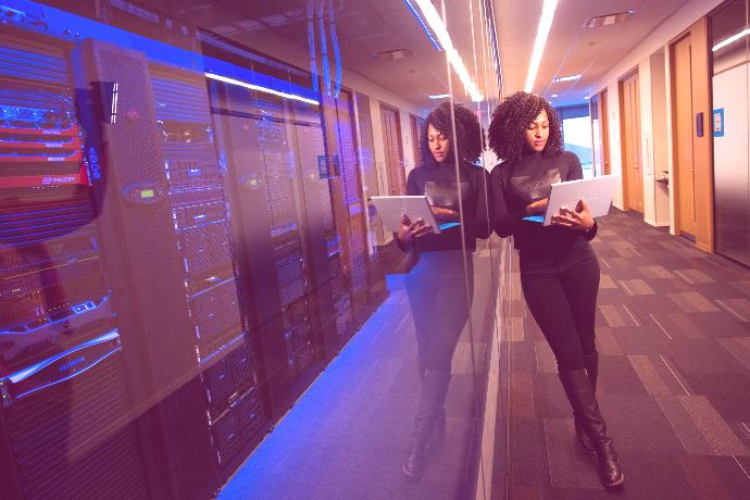 Photo of a woman with a laptop in a data center.