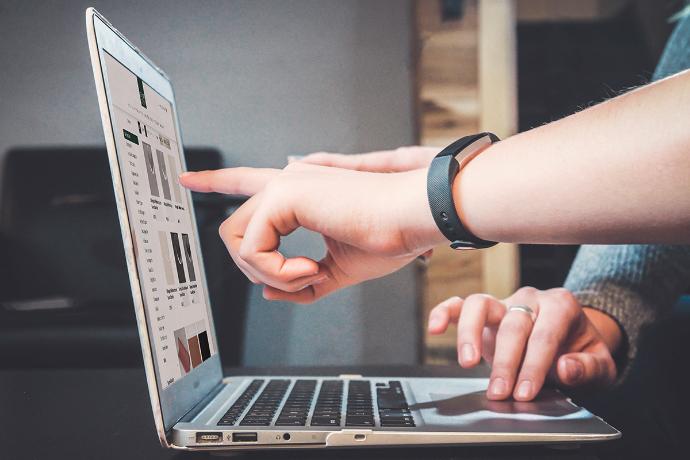 Photo of a laptop with our B2B shop open and hands pointing to the screen.