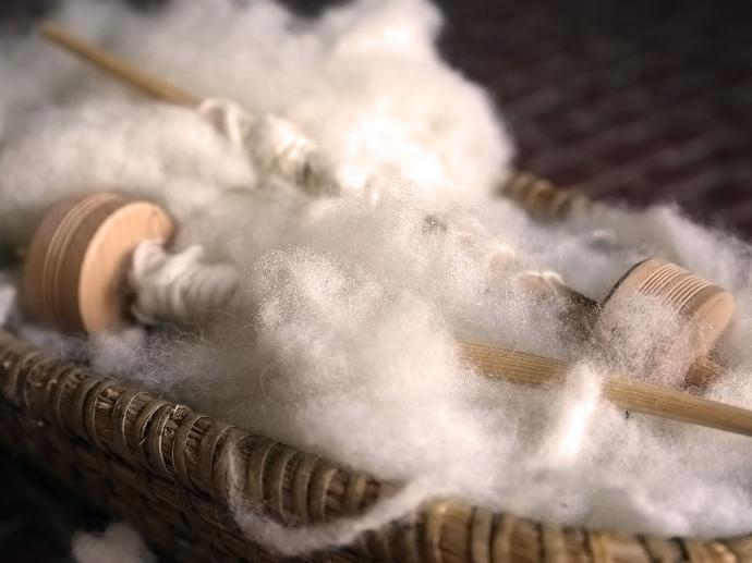 Close-up of spindles with white wool attached.