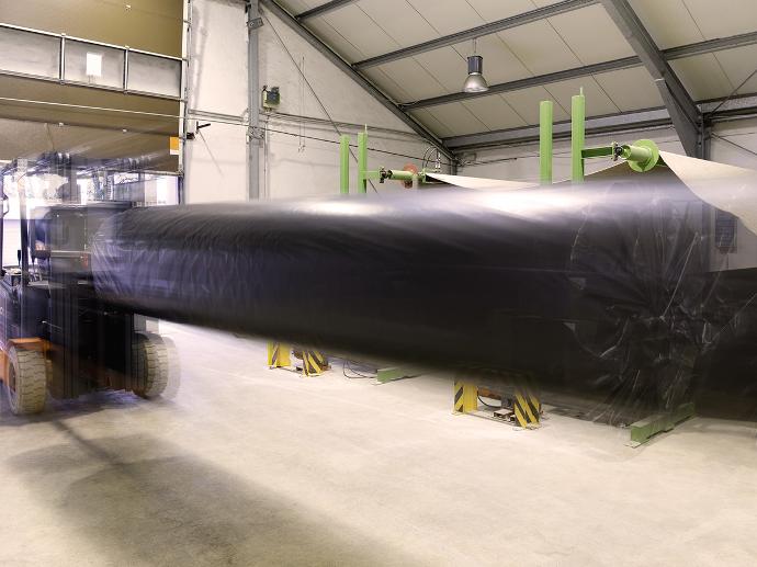 Photomontage of a forklift with a large roll of carpet on a mandrel driving through a hall.